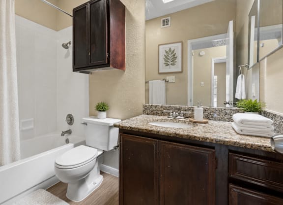 A white toilet sits in a bathroom with a brown cabinet.