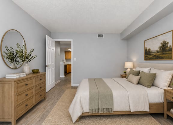 A bedroom with a large bed, a dresser, and a painting on the wall.