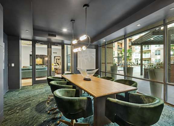 A conference room with a long table and green chairs.
