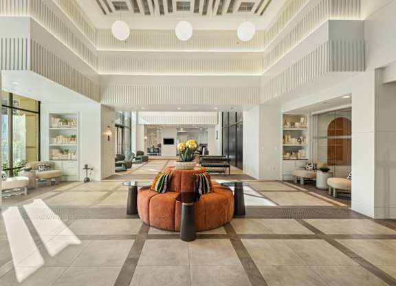 A spacious living room with a central orange sofa and a variety of seating options.