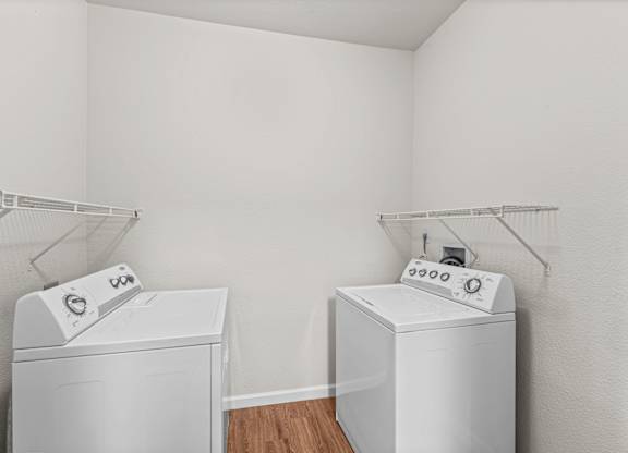 two white washers and dryers in a room with white walls and wood floor