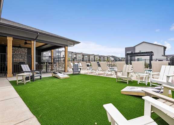 A patio with white chairs and a green lawn.