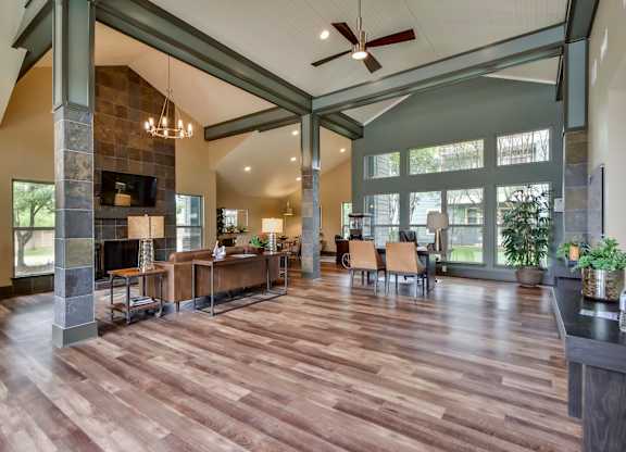 A spacious living room with wood flooring and a stone fireplace.