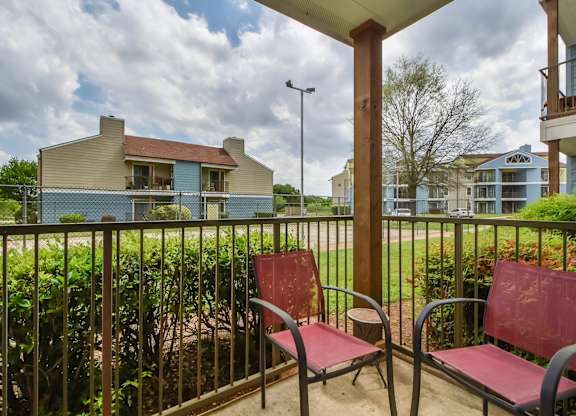 Two red chairs are on a patio.