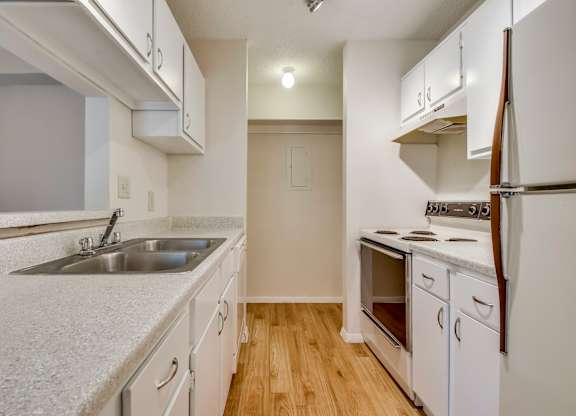 A kitchen with white cabinets and a white fridge.