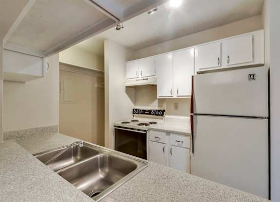 A kitchen with white cabinets and a stainless steel sink.