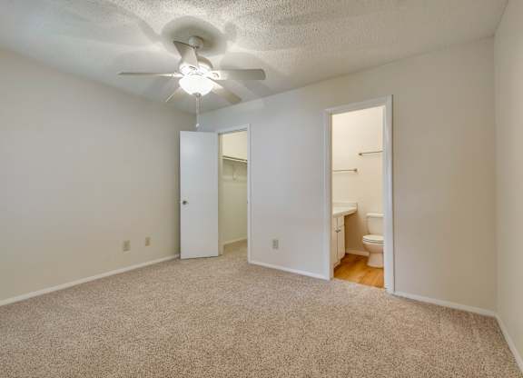 A room with a carpeted floor and a ceiling fan.