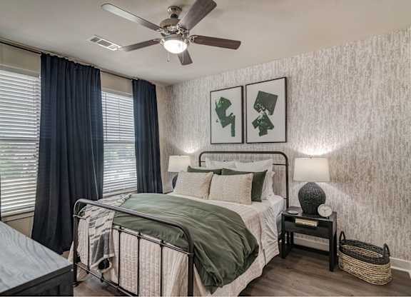 A bedroom with a bed, nightstand, and two pictures on the wall.