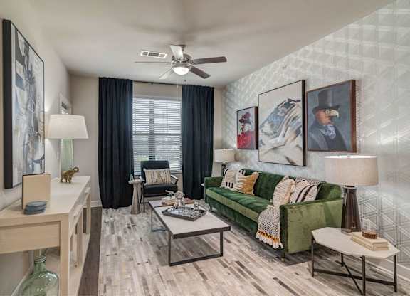 A living room with a green couch and a ceiling fan.
