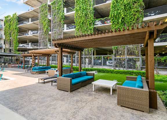 A patio area with a wooden pergola and woven furniture.