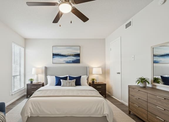 A bedroom with a bed, a chair, and a ceiling fan.