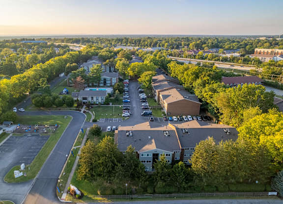A parking lot is surrounded by trees and buildings.