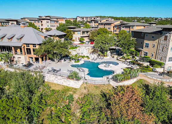 A bird's eye view of a resort with a swimming pool surrounded by buildings.