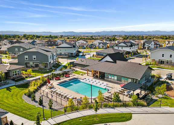 A large swimming pool surrounded by a black fence and a grassy area with a few trees.