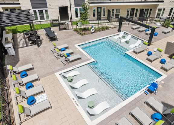 A pool surrounded by lounge chairs and umbrellas.