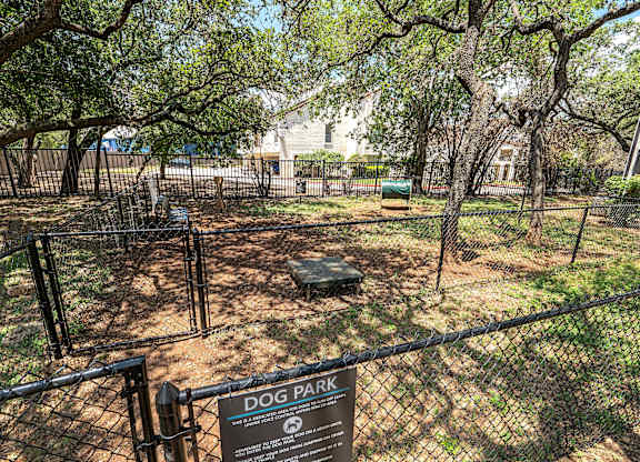 A dog park sign is displayed on a fence.