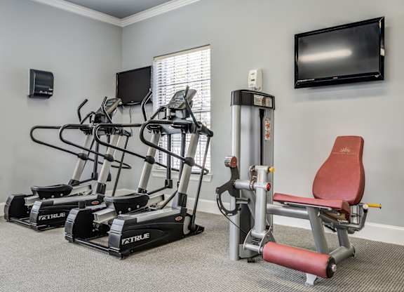 A home gym with a treadmill, elliptical trainer, and a stationary bike.