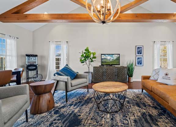 A living room with a brown couch, a coffee table, and a chandelier.