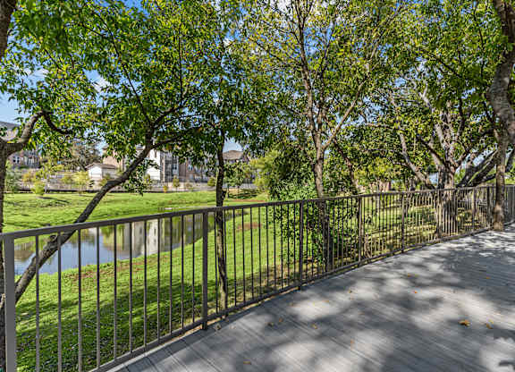 A wooden walkway with a metal railing runs through a grassy area.