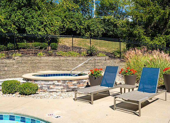 A pool with a stone border and a fence behind it.