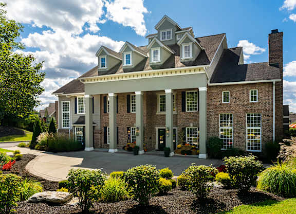 A large house with a front porch and a landscaped yard.
