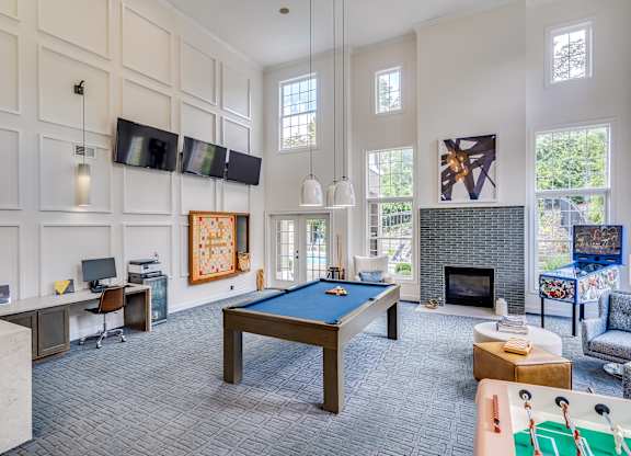 A billiard table is in the middle of a room with a television and a fireplace.