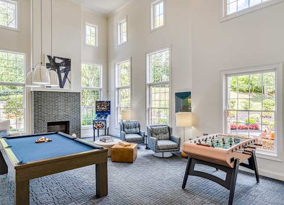 A pool table and a foosball table are in a large room with a fireplace.