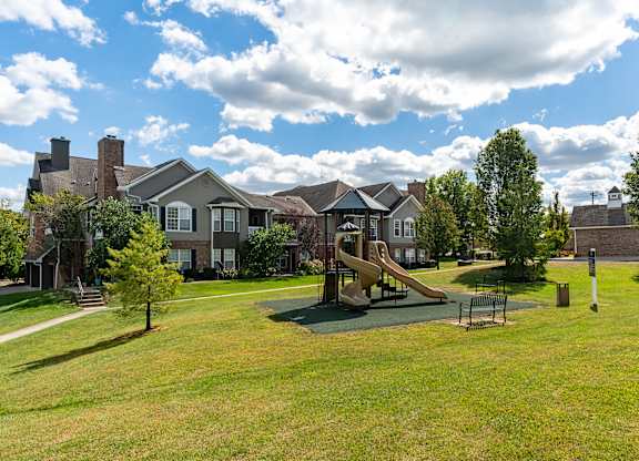 A playground with a slide and a swing set in a grassy area.