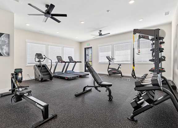A gym with a variety of equipment including treadmills, rowing machines, and weight benches.