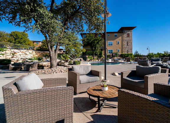 A patio with brown wicker furniture and a tree.