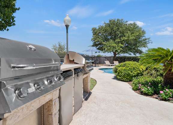 A large outdoor grill is on a patio next to a pool.