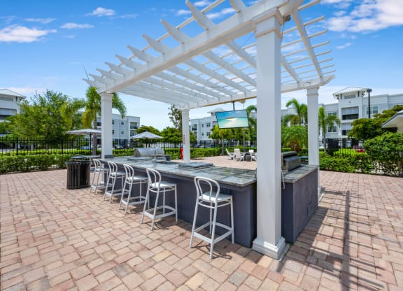 an outdoor bar with white columns and a white pergola on top of a brick patio