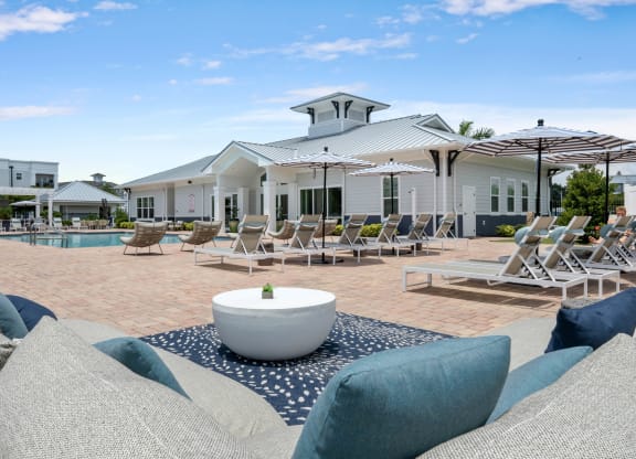 a pool with lounge chairs and umbrellas at the enclave at woodbridge apartments in sugar
