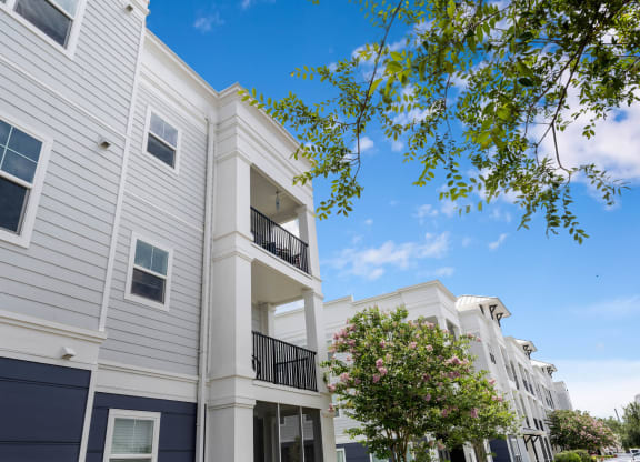 a picture of a white apartment building with a blue sky in the background