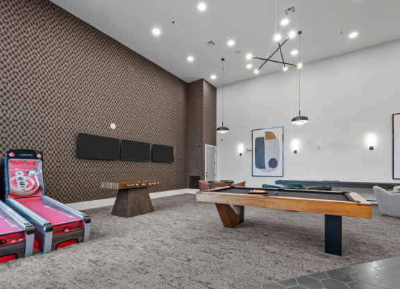 two pool tables in a room with televisions and other gaming equipment