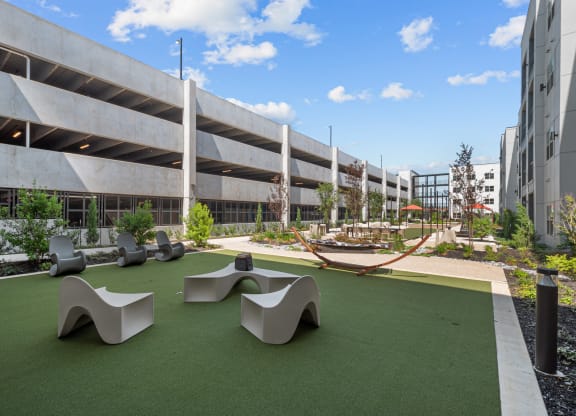 a courtyard with benches and grass in front of a building