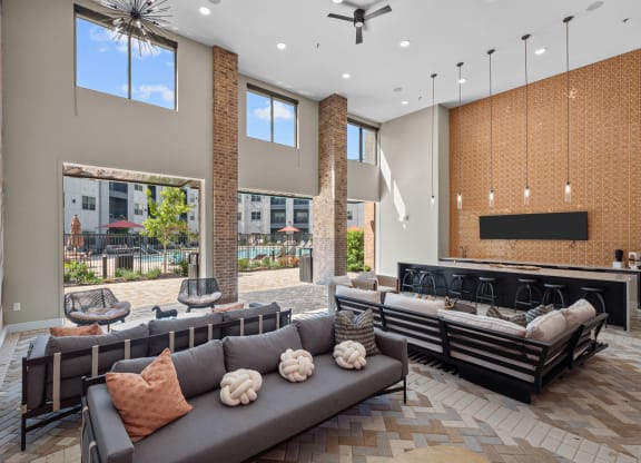 a large lobby with couches and chairs and a bar and windows