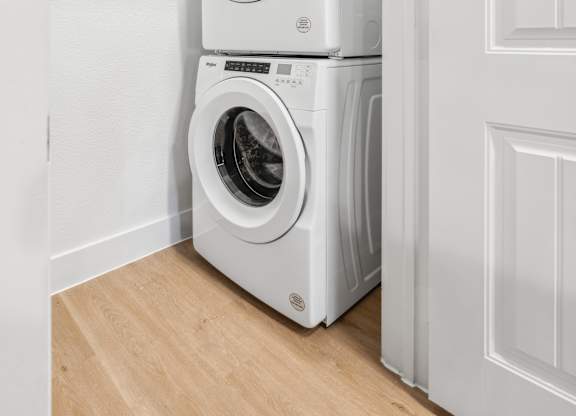 A white washing machine and dryer stacked on top of each other in a laundry room.