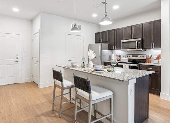 A kitchen with a white island and black chairs.