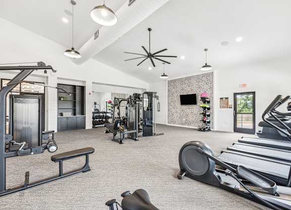 A gym with treadmills, weights, and exercise equipment.