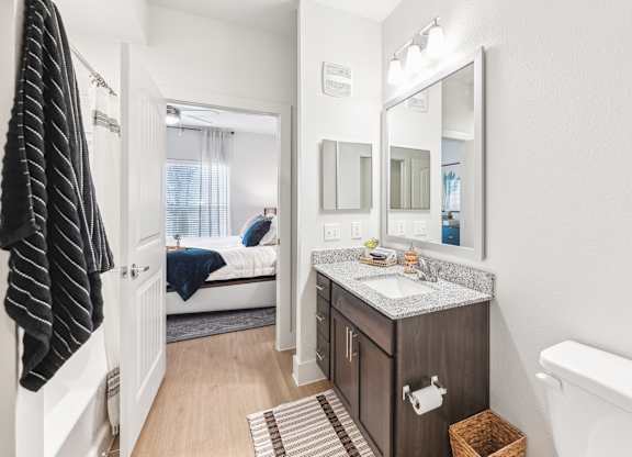 A bathroom with a toilet, sink, and mirror.