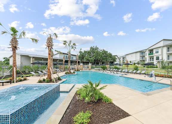 A swimming pool surrounded by palm trees and lounge chairs.