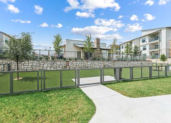 A modern building with a stone wall and a metal fence in front of it.
