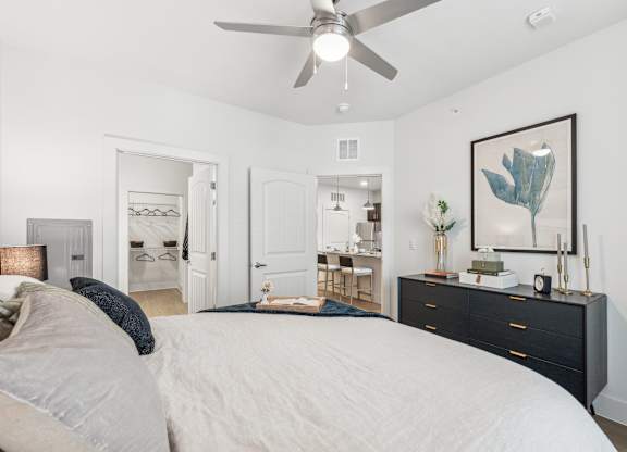A bedroom with a large bed, a dresser, and a ceiling fan.