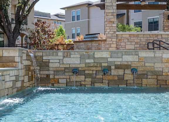 A pool with a waterfall feature in the middle of it.