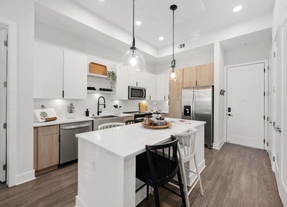 an open kitchen with a large white island with two black chairs