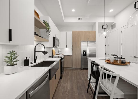 a modern kitchen with white counter tops and a large island with stools