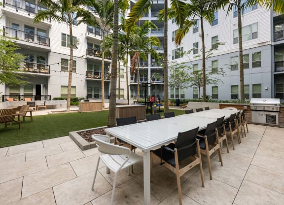 a long communal table and chairs in an apartment courtyard