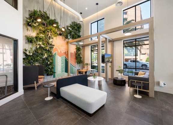 a lobby with couches and chairs and a wall of plants