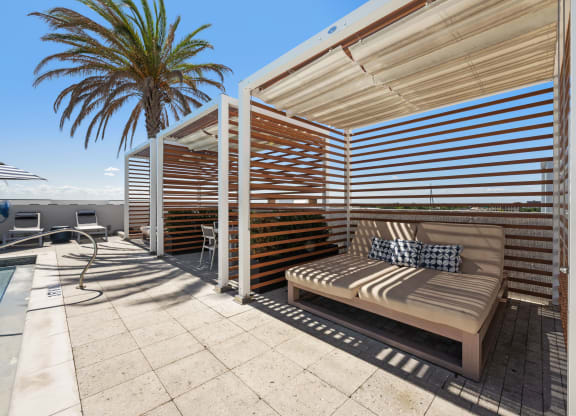 a covered patio with a bench and a palm tree